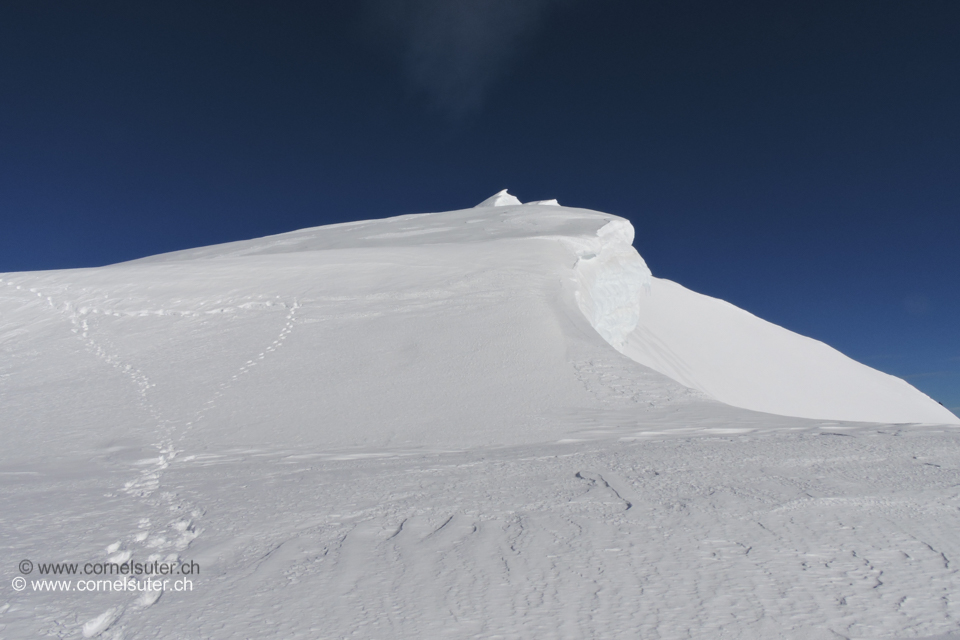 Nach diesem Steilstück wird es flacher weiter in den Spuren oder auf nicht tragendem Schnee hinauf zum Gipfel, kurz unterhalb des Gipfels nochmals wenige Meter eine steile Traversierung aber auf hartem griffigem Schnee.