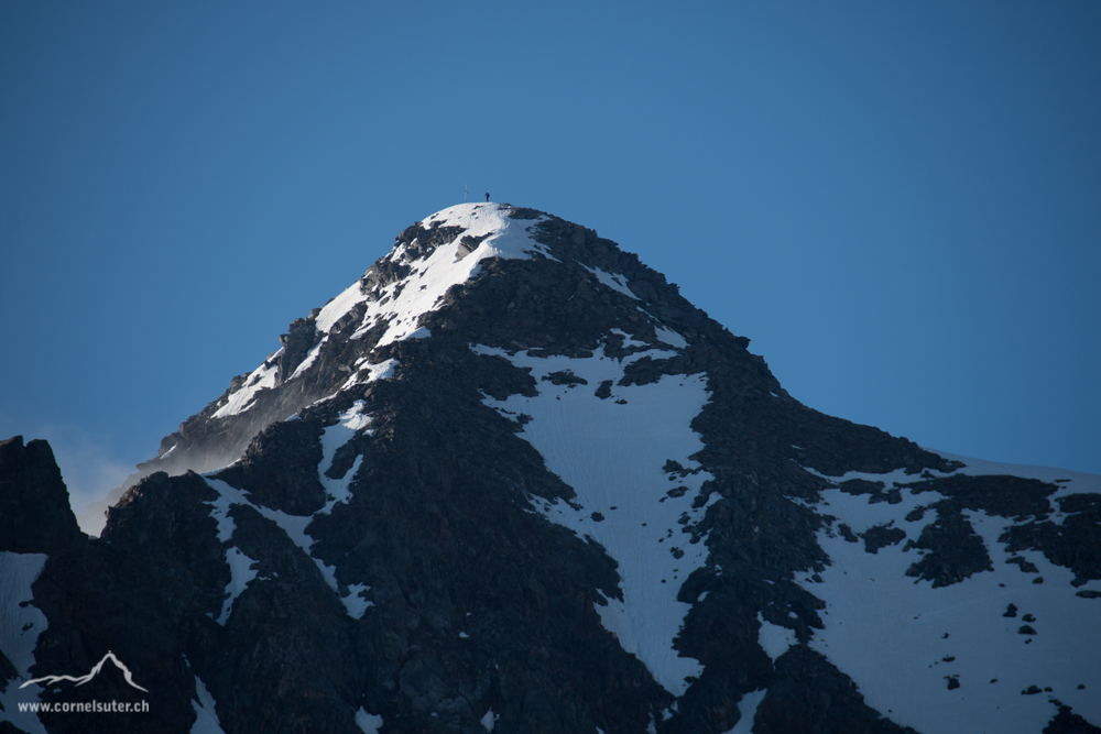 Ein Bergsteiger ist bereits auf dem Gipfel.