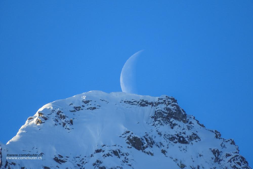 Der Mond über einem Berggipfel.