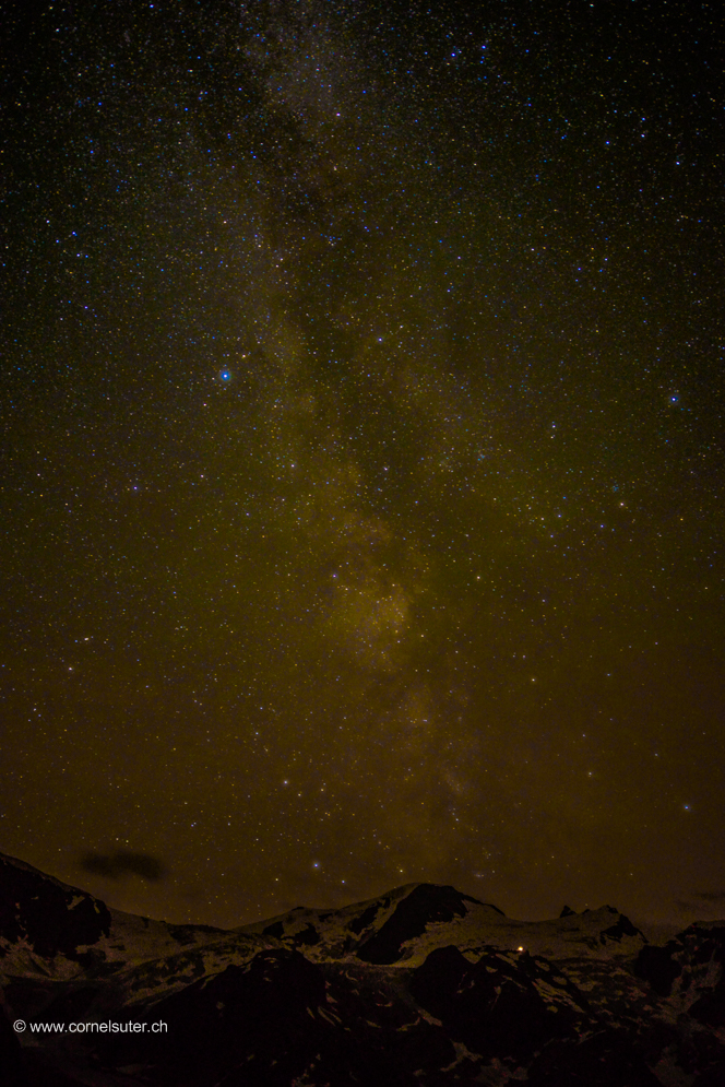 SAC Tierberglihütte am Rande zum Universum. Fasziniert von meinem ersten Bild von der Milchstrasse auf dem Furkapass, reiste ich für mein zweites Bild auf den Sustenpass 2224m. Angekommen auf dem Pass schleicht die Bewölkung in der Abenddämmerung herum, somit reicht es noch für Zeitraffer Aufnahmen. Ein paar Stunden später war es dann soweit, die Wolken haben sich verzogen, die Sterne zeigen sich die Milchstrasse ist von blossem Auge zu erkennen. Stativ aufrichten Nikon Kamera D800 einstellen und los geht’s. Alleine und Niemand auf dem Pass hin und wieder düst ein Auto vorbei. Die Kamera richte ich auf die gegen über liegende Talseite zum Gwächtenhorn 3420m und zur SAC Tierberglihütte 2798m wo noch Licht ist, so gebe ich diesem Bild den Titel,  SAC Tierberglihütte am Rande zum Universum. Die Tierberglihütte ist der helle Punkt direkt unter dem Gwächtenhorn 3420m. Die Milchstrasse erhebt sich über dem Gwächtenhorn 3420m.